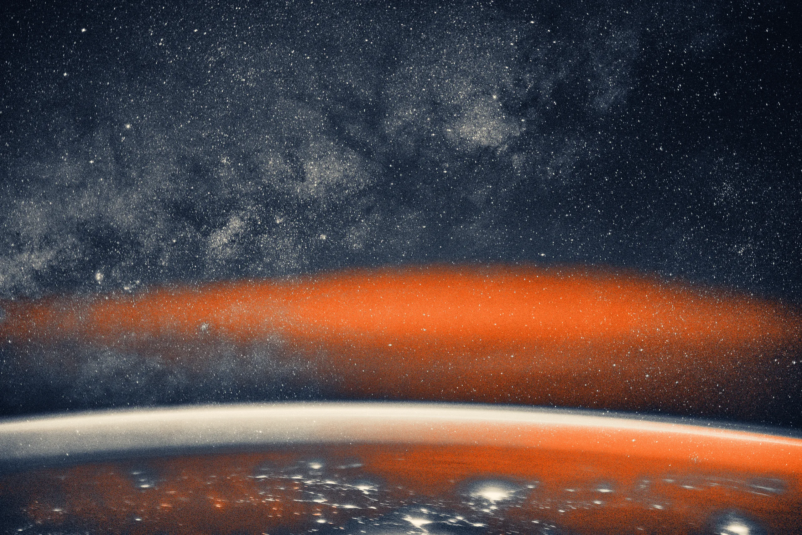 The Milky Way spans the night sky above a bright orange-yellow airglow
