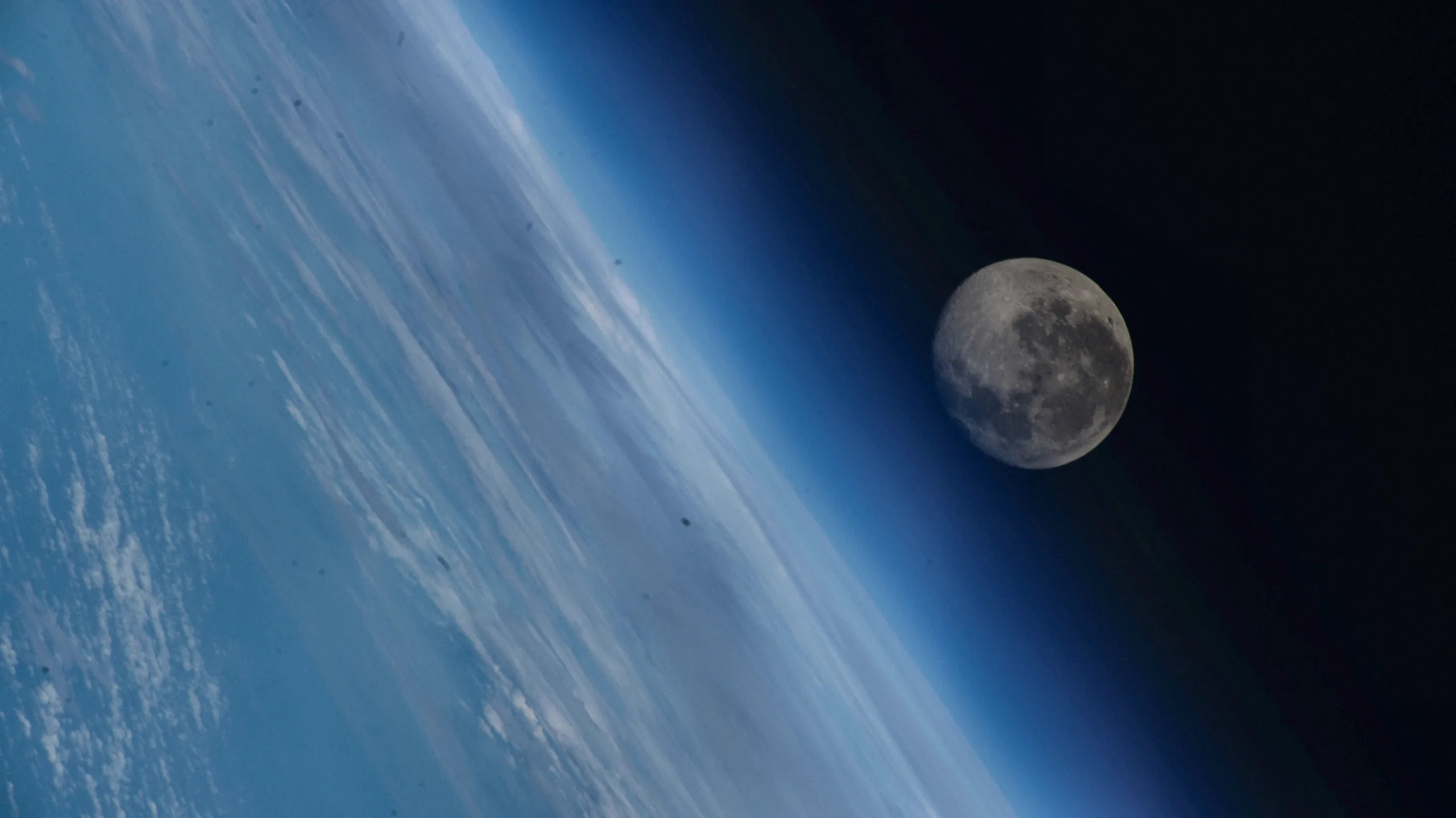 The waning gibbous Moon appears above Earth’s blue atmosphere