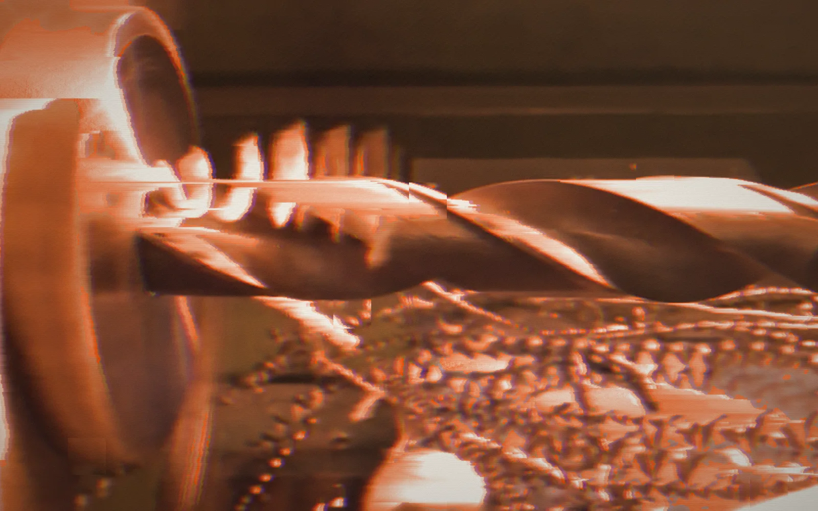 Drilling a gear blank — Wikimedia Commons, 2014; the film broken up by digital glitches, pixel-sorted in the brand's orange