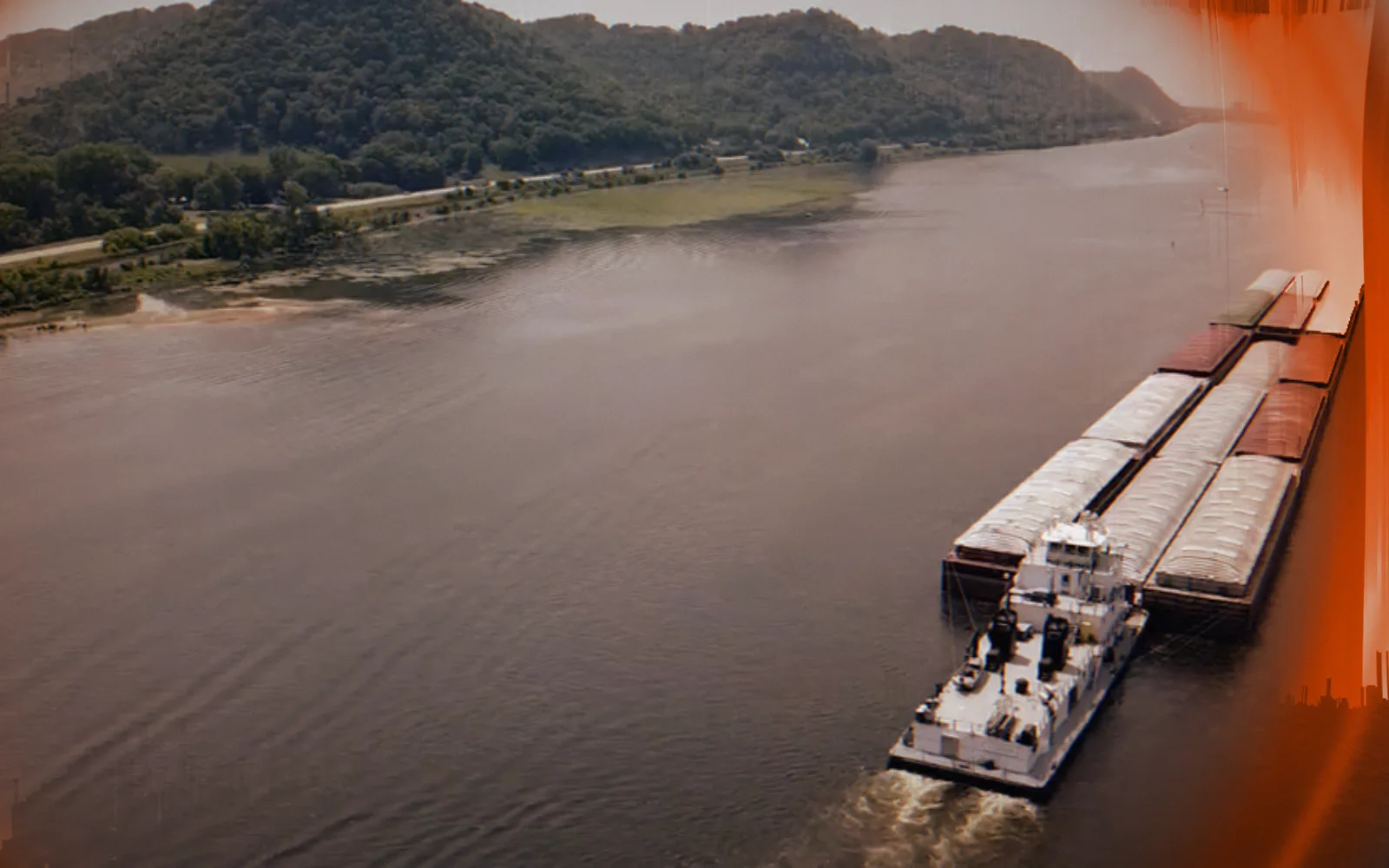 Towboat and barges — Mississippi River, 2023; a disruption moves through the picture as a ring, pixel-sorted in the brand's orange